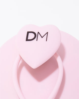 Close-up of DESIGNME scalp brush heart-shaped handle with DM logo