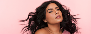 Model with voluminous curly hair against a pink background.