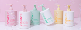 Six large bottles of different DESIGNME shampoo and conditioner surrounded by bubbles.