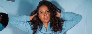 Model with 3A curls, showing shiny, bouncy, and defined curls against a blue background.