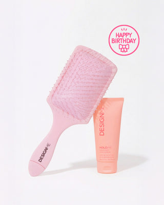 HOLD.ME styling cream & our detangling paddle brush on a grey background with a sticker that says 'Happy Birthday' in top right corner.