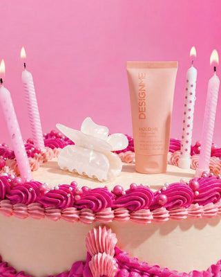 Butterfly hair clip and HOLD.ME styling cream sit on a cute pink cake.