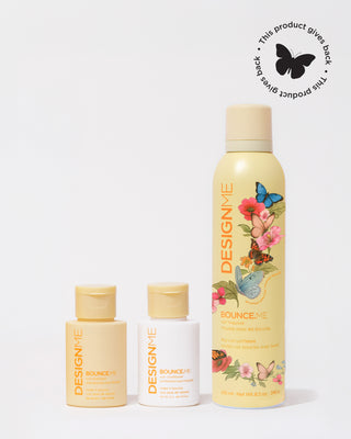 Limited edition womens month BOUNCE.ME curl mousse, BOUNCE.ME curl shampoo and BOUNCE.ME curl conditioner sit on a grey background. A sticker in the top right corner with 'this product gives back'.