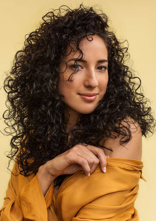 Model with 2C hair showing defined, bouncy curls, highlighting texture and curl pattern.