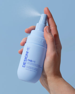 FAB.ME multi-vitamin leave-in treatment spraying against a blue background.