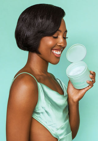 Model with beautiful, glossy hair holding GLOSS.ME Hydrating Treatment Mask, symbolizing healthy, hydrated hair.